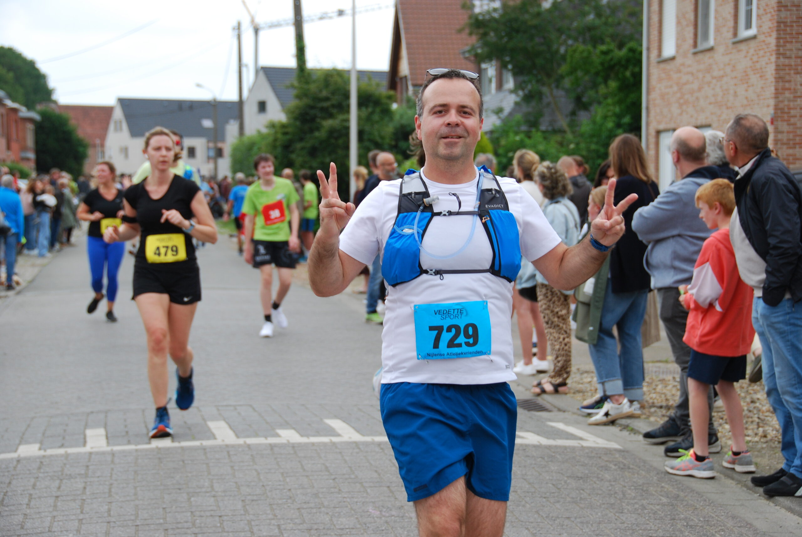 Runner wearing hydration vest and running watch during first half marathon race, using it as preparation test for upcoming goal race.