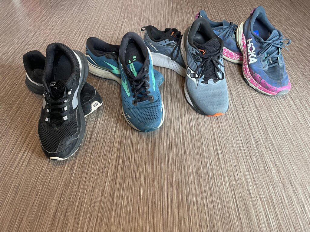 Four running shoes: Decathlon Kalenji Active Grip starter shoe, then Brooks Ghost 15, Hoka Speedgoat 6 trail shoe, and Saucony Triumph 22 - all chosen after professional gait analysis