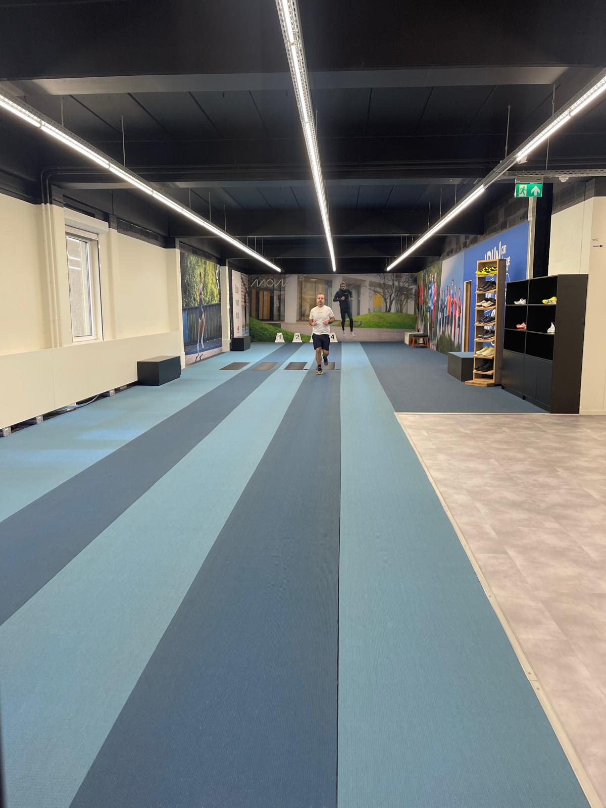 Running on an indoor track during gait analysis in a running store, just after passing the rubber band that measures foot strike.
