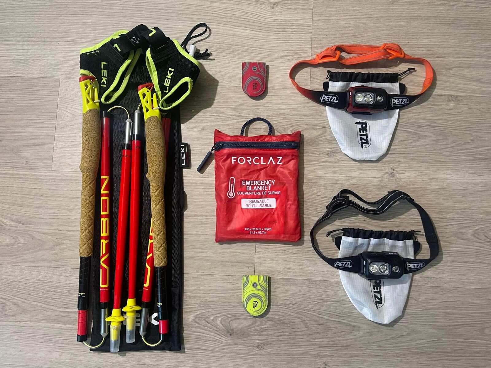 Flat lay photo of specialized trail running gear including Leki poles, head torches, LED markers, and safety blanket.