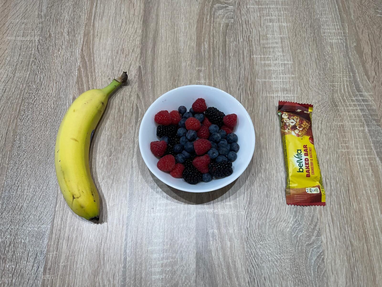Pre-run snack with mixed forest berries, a banana, and a BelVita cereal bar for quick carbohydrates before running.