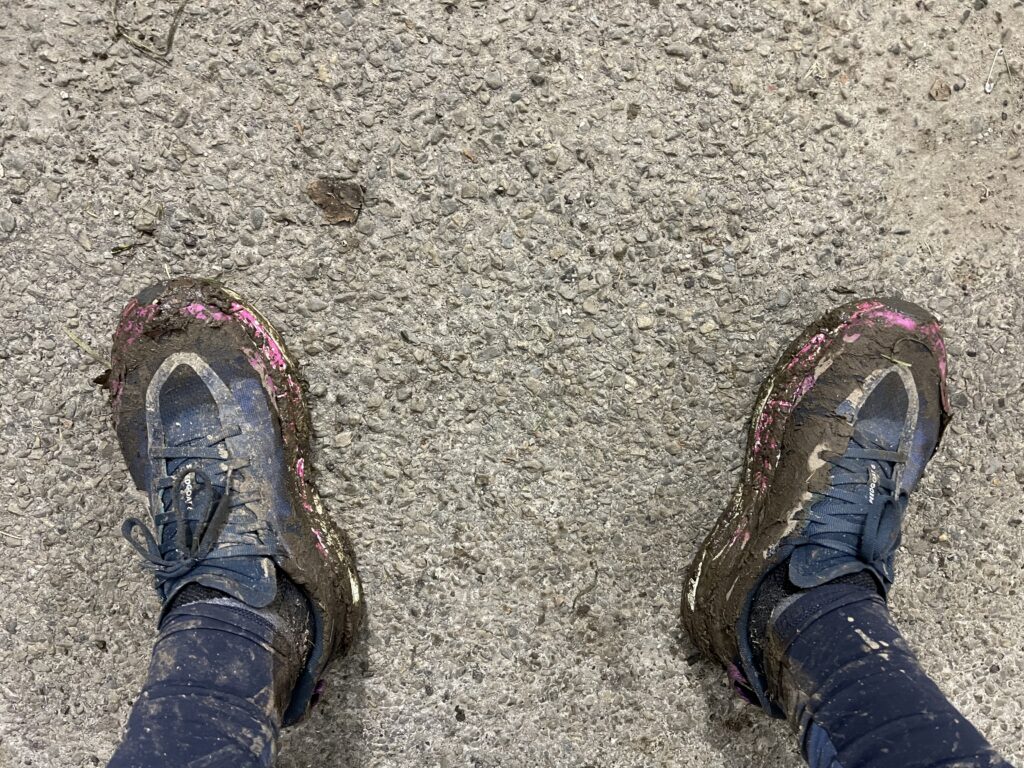 Muddy trail running shoes at the finish line of Trail du Hoyoux 2024, showing exhaustion and effort.
