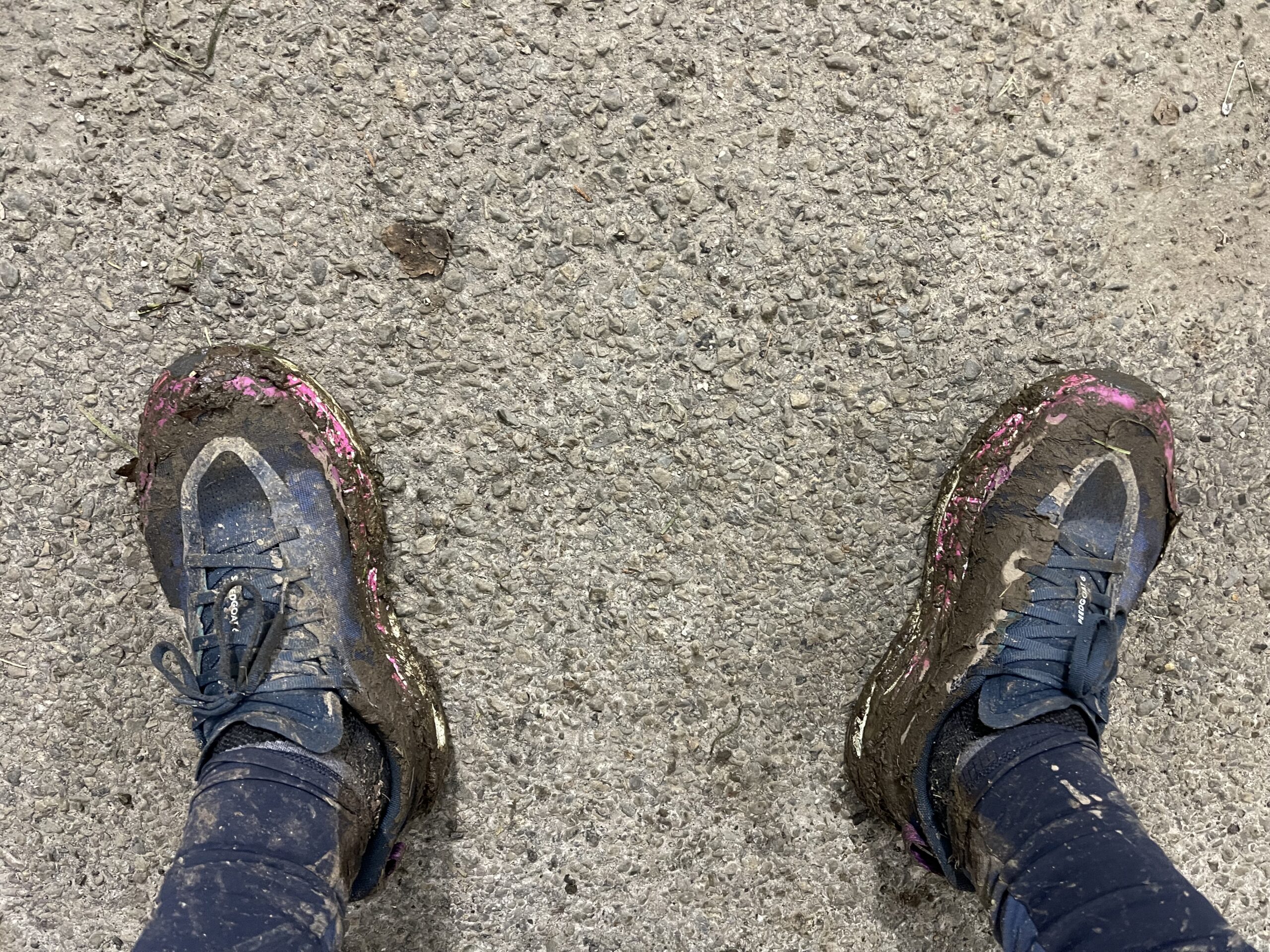 Muddy trail running shoes at the finish line of Trail du Hoyoux 2024, showing exhaustion and effort.